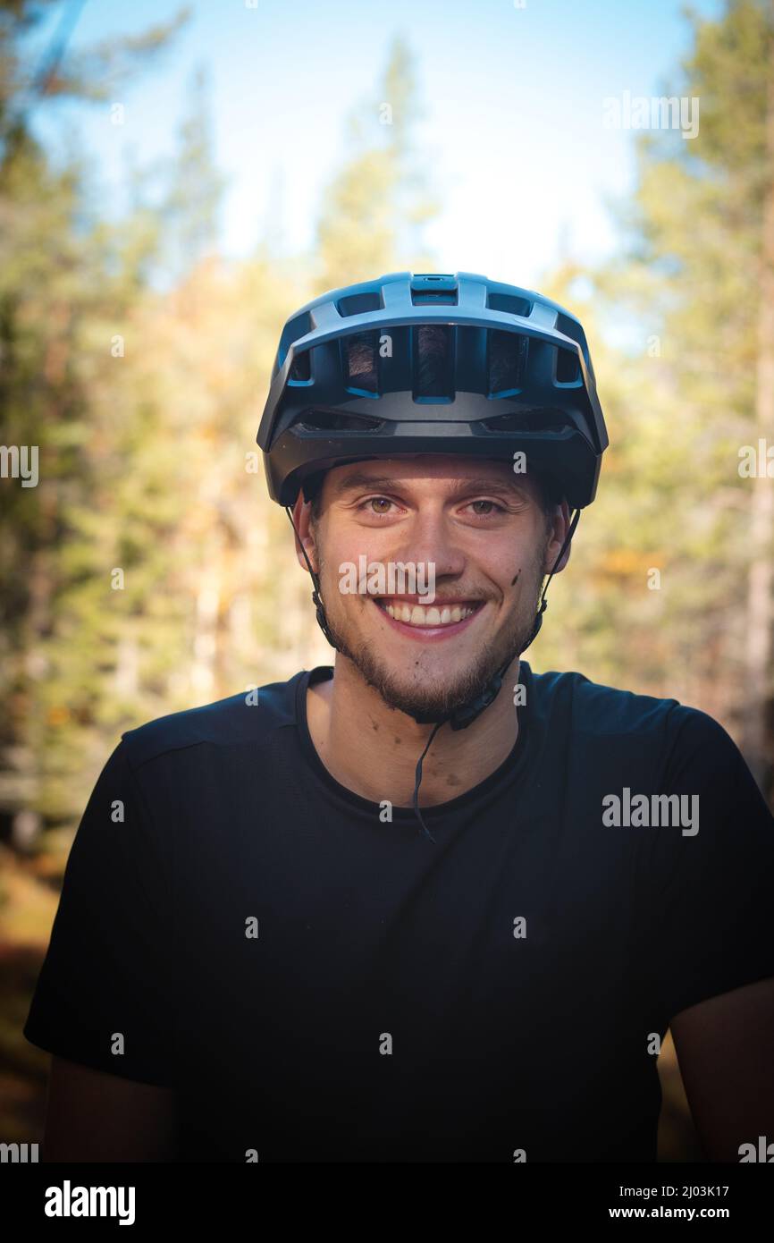 Freizeitsportler lächelt zufrieden nach einem anspruchsvollen Trail im Schlamm. Aufrichtiges Porträt eines jungen Athleten mit einem wahren Lächeln und Schlamm auf Hallo Stockfoto