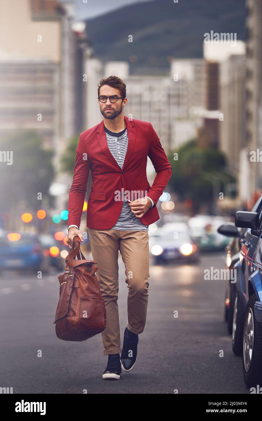 Ich werde auf die eine oder andere Weise dorthin gelangen. Aufnahme eines hübschen jungen Mannes, der auf der Straße unterwegs ist, während er seine Tasche mit entschlossenem Blick trägt. Stockfoto