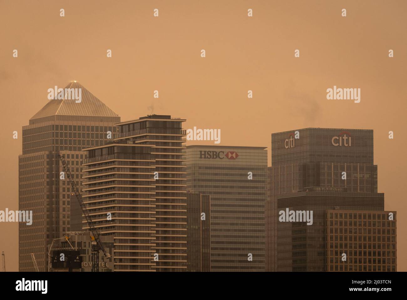 London, Großbritannien. 16.. März 2022. UK Wetter: Staubwolke der Sahara. Canary Wharf-Gebäude, die durch orangefarbene Töne als Staubwolke aus den Sahara-Regionen sichtbar sind und derzeit 2km über dem Boden liegen, bewegen sich quer durch Europa. Kredit: Guy Corbishley/Alamy Live Nachrichten Stockfoto