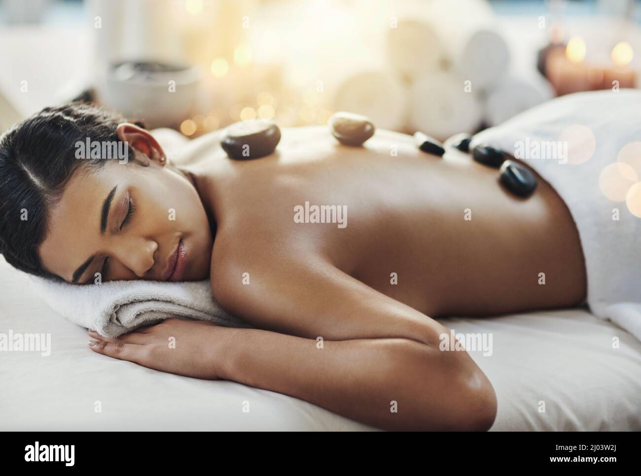 Sagen Sie Auf Wiedersehen zu diesen Muskelkater. Aufnahme einer jungen Frau, die in einem Spa eine Hot-Stone-Massage bekommt. Stockfoto
