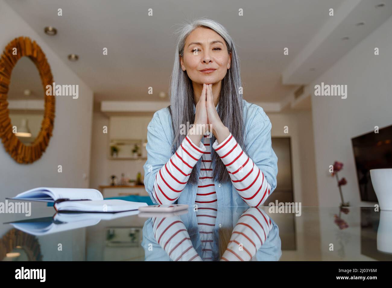 Frau sitzt am Tisch und tut Gebetstus Stockfoto