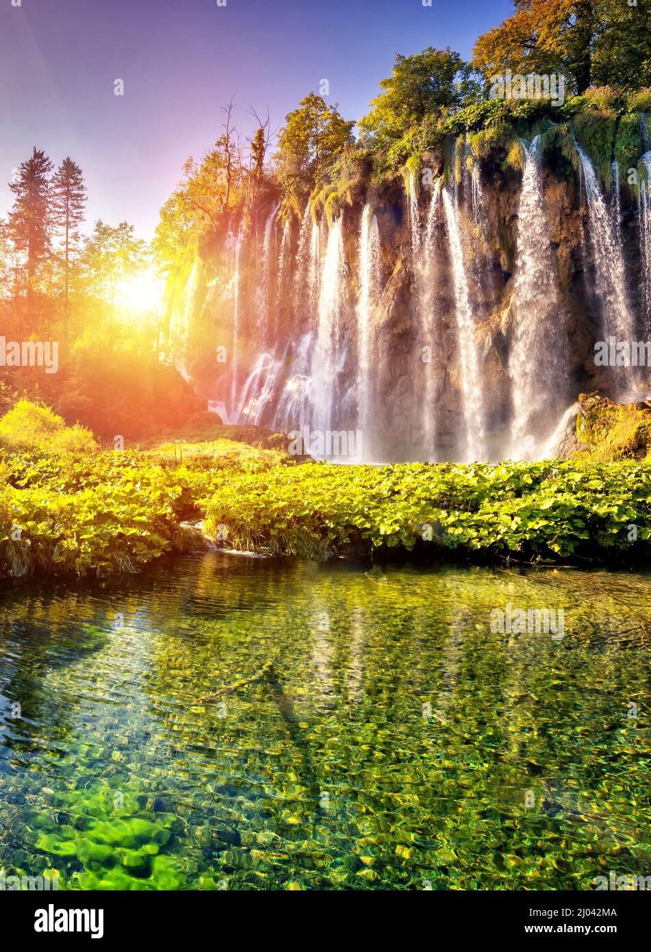 Majestätischer Blick auf den Wasserfall mit türkisfarbenem Wasser und sonnigen Balken im Nationalpark Plitvicer Seen. Der Wald leuchtet durch Sonnenlicht. Kroatien. Europa. Dramatisch Stockfoto