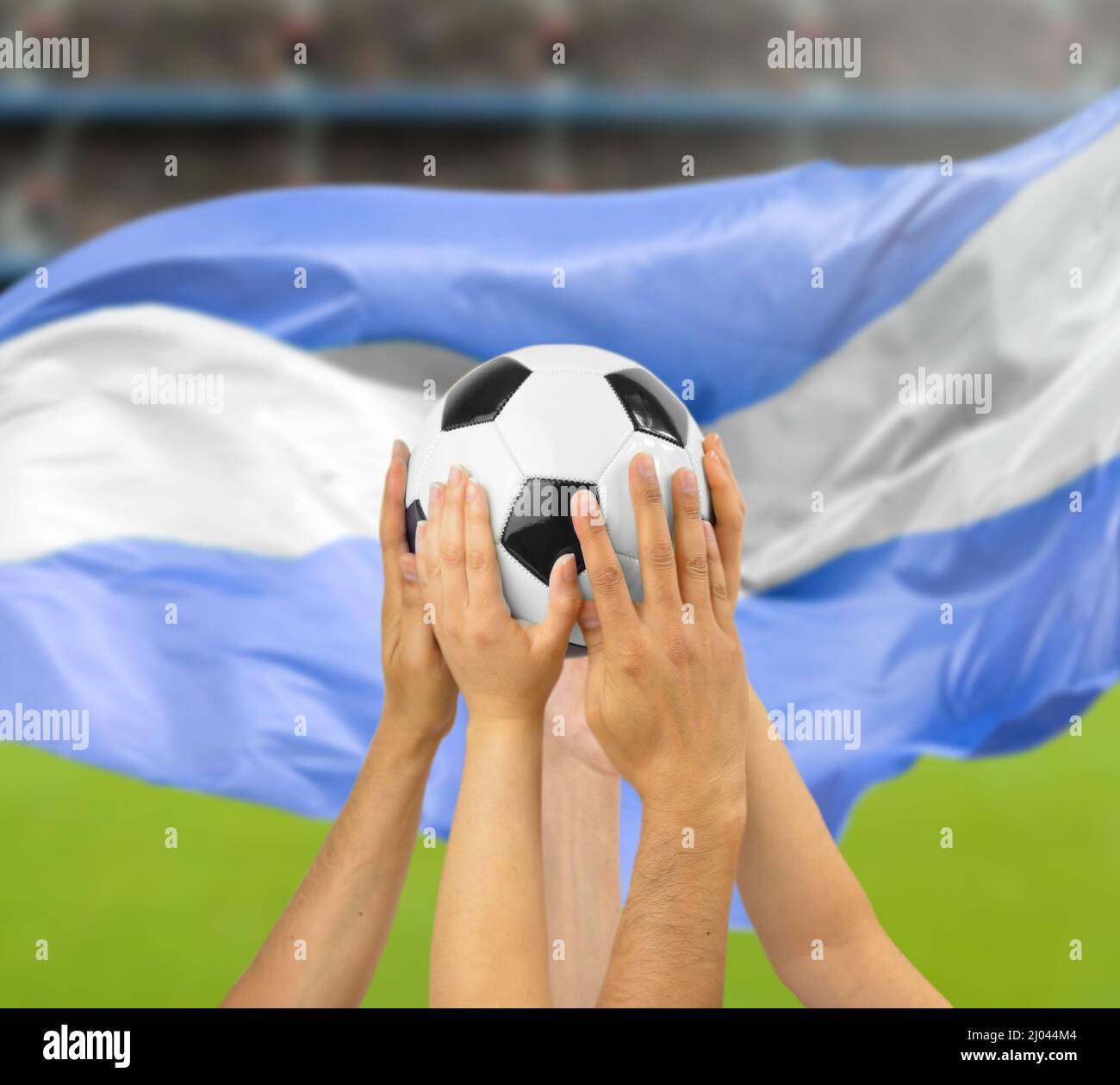 Eine Gruppe von Fußballspielern, die einen Fußball im Fußballstadion mit argentinischer Flagge halten Stockfoto