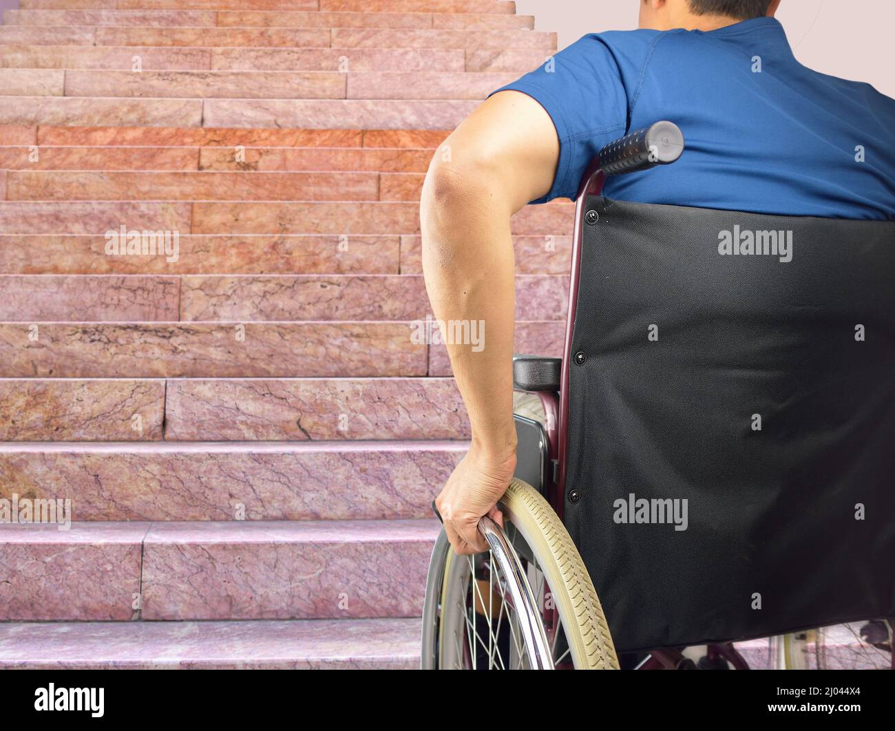 Rückansicht niedriger Abschnitt eines jungen behinderten Mannes im Rollstuhl vor einer Treppe in einem Haus Stockfoto