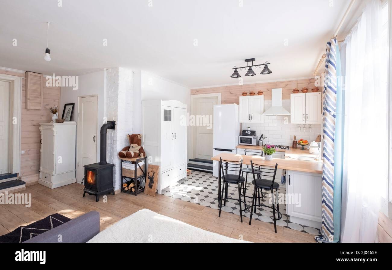 Interieur eines hellen Studio-Zimmer mit einem skandinavischen Stil Kamin in einem privaten Haus, wo Wohnzimmer mit Küche kombiniert wird. In einem Land hous Stockfoto