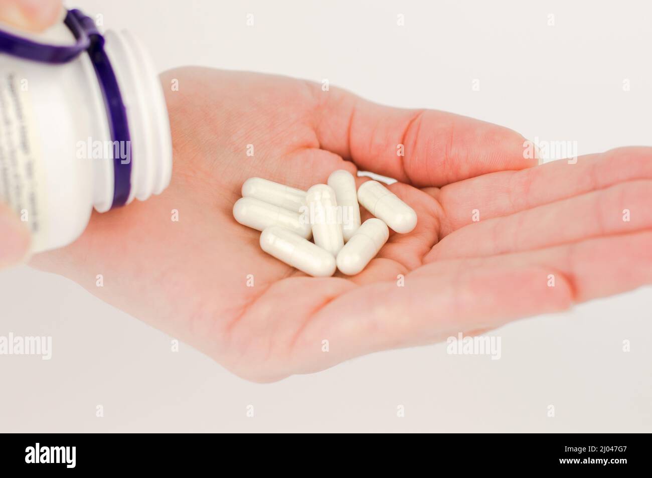 Weiße Kapsel Pillen in einer weiblichen Hand Nahaufnahme. Pillen für unerwünschte Schwangerschaft, orale Empfängnisverhütung. Stockfoto