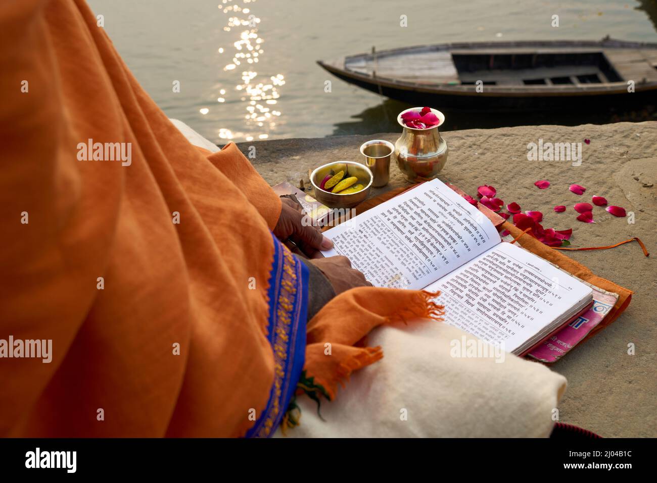 Indien. Varanasi Benares Uttar Pradesh. Ein Mann, der heilige Texte des hinduismus liest und am Fluss Ganges bei Sonnenaufgang betet Stockfoto