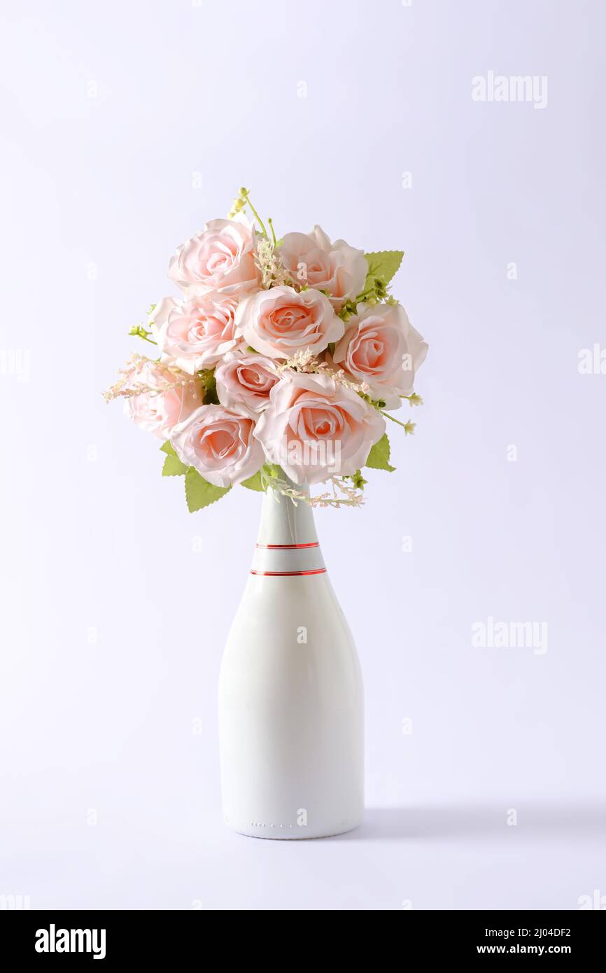 Bouquet von frischen rosafarbenen Blumen in einer schicken, unbeschrifteten weißen Champagnerflasche über Grün mit Kopierplatz für den Valentinstag Stockfoto
