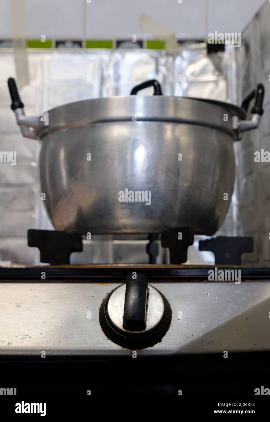 Der große Metalltopf auf dem Gasherd nach dem Kochen in der Küche des Stadthauses, selektiver Fokus auf den Gasherd-Schalter, Vorderansicht mit der Kopie Stockfoto