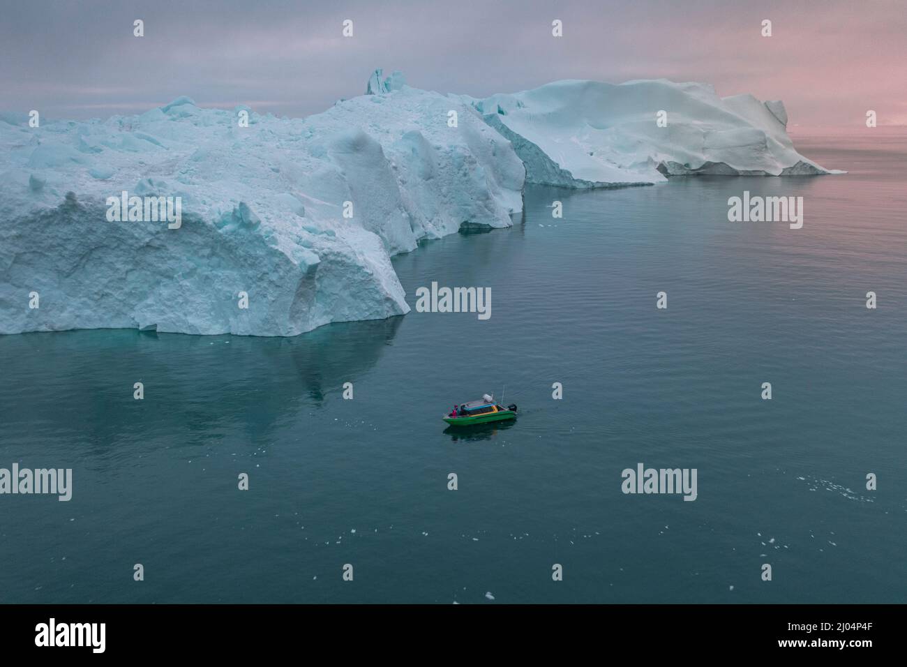 Kleines Boot, das aus der Luft vor extremen Eisbergen segelt Stockfoto