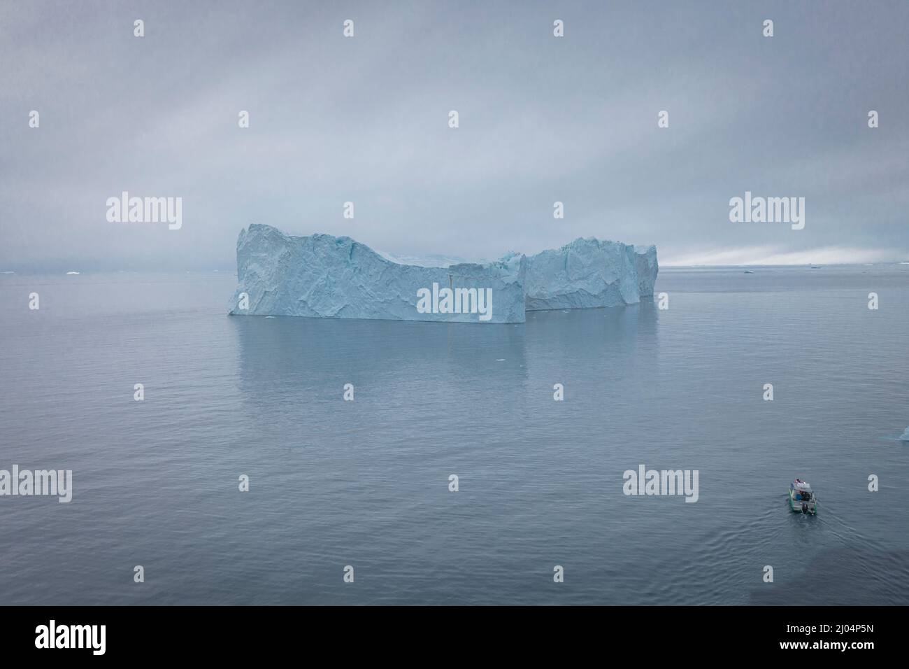 Kleines Boot, das aus der Luft vor extremen Eisbergen segelt Stockfoto