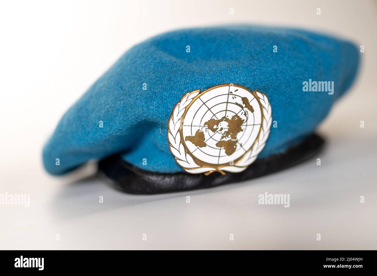 Blaue Baskenmütze der Vereinten Nationen mit UN-Abzeichen auf weißem Hintergrund Stockfoto