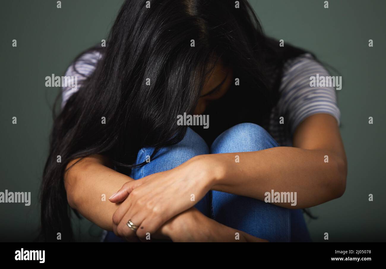 Manchmal willst du nur deinen Kopf begraben. Zugeschnittene Aufnahme einer nicht erkennbaren jungen Frau, die vor grünem Hintergrund im Studio deprimiert aussieht. Stockfoto