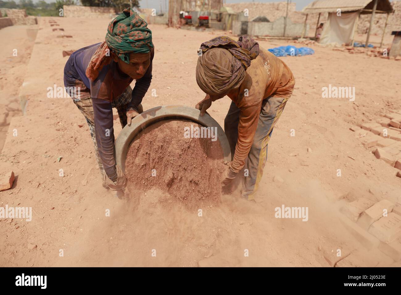Bangladeschische Männer arbeiten auf einem Ziegelfeld in Keraniganj, in der Nähe von Dhaka, Bangladesch, 7. März 2022. Die Emission der riesigen Menge der giftigen Elemente aus dem Ziegelstein kil Stockfoto