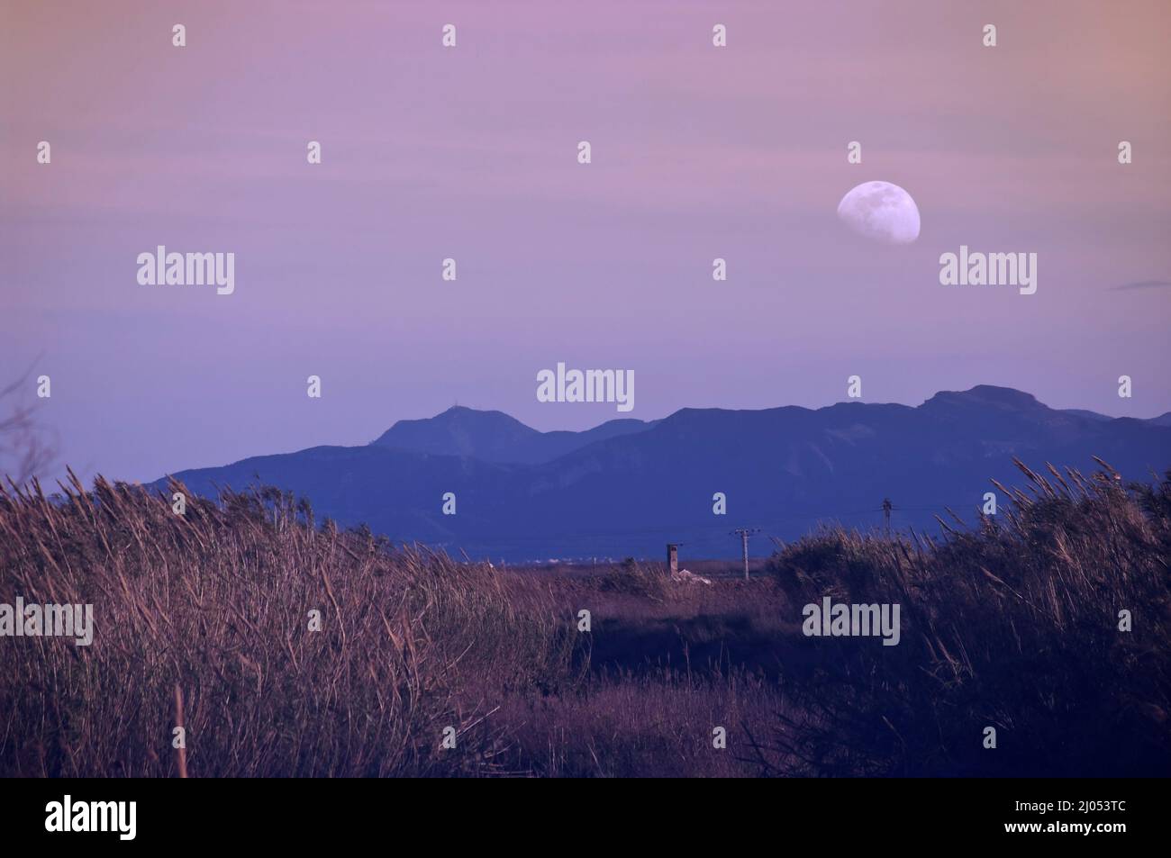 In einem Sonnenuntergang, aus den Bergen erscheint der Mond in einem Zustand der Ruhe. Stockfoto