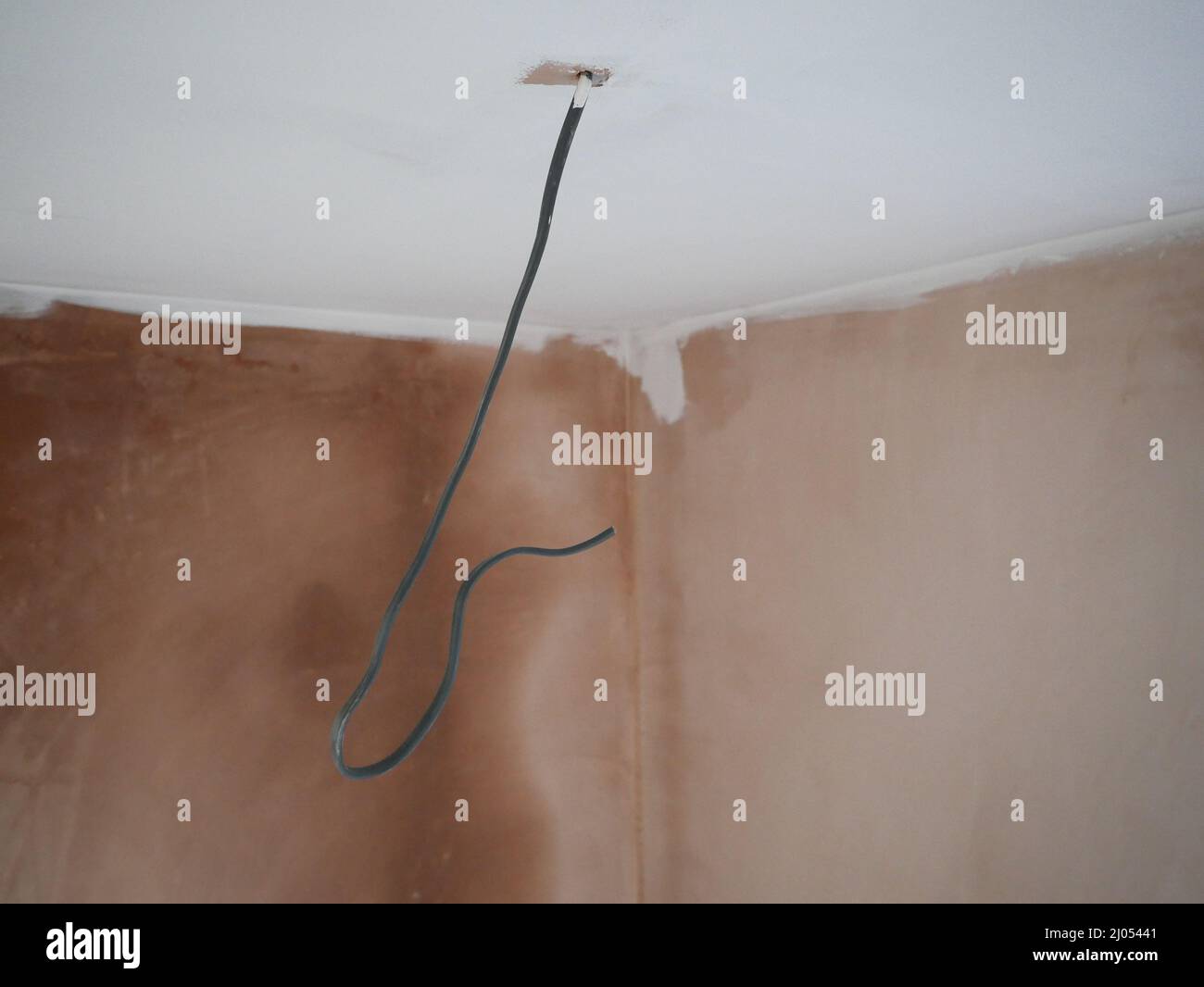 Befestigen Sie zunächst Elektrokabel in einer frisch verputzten Wand. Stockfoto