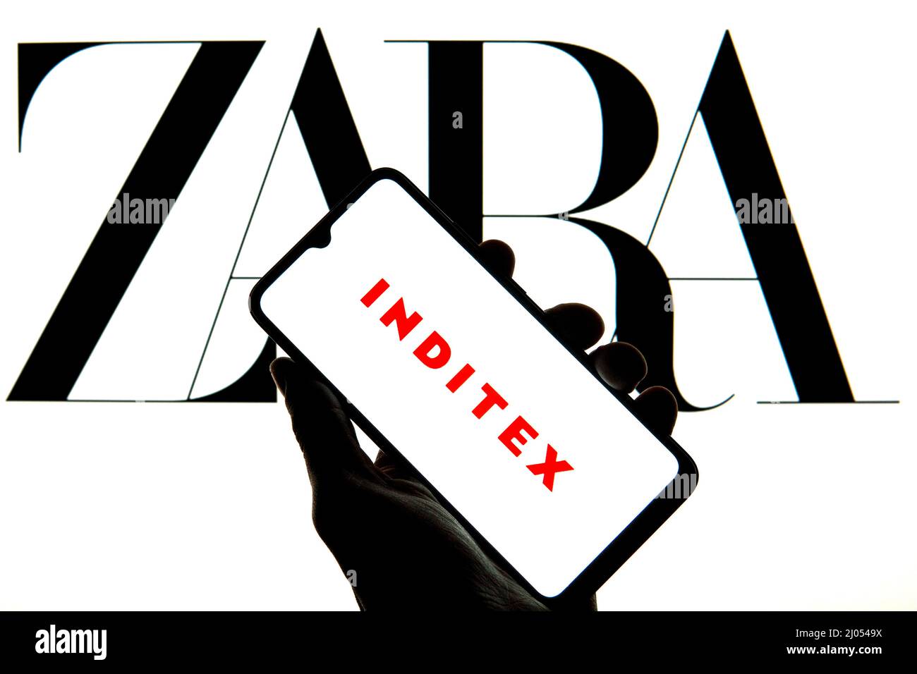 In dieser Abbildung ist ein Inditex-Logo auf einem Smartphone mit einem Zara-Logo im Hintergrund zu sehen. Stockfoto