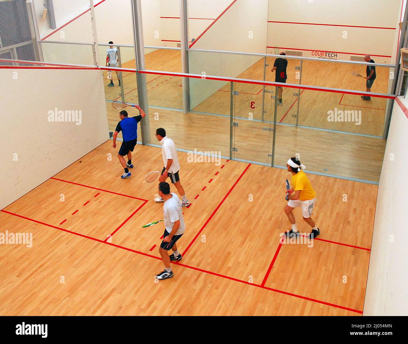 Vier Männer spielen Doppel auf einem speziellen Doppel Squashplatz. Es gibt zwei Teams, die ein schnelles und ein wenig gefährliches Spiel spielen. Die meisten Squashplätze sind Einzelplätze und es ist selten, einen speziell gefertigten Doppelplatz zu finden. Die Spieler sind im Coolhurst Squash Club in Crouch End, Nord-London, England. Stockfoto