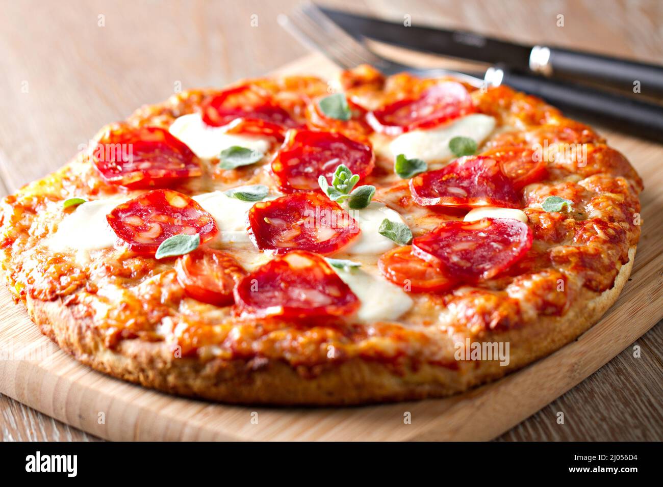 Pizza mit Pfefferoni-Wurst und Käse auf einem Holzbrett auf einem Holzhintergrund Stockfoto