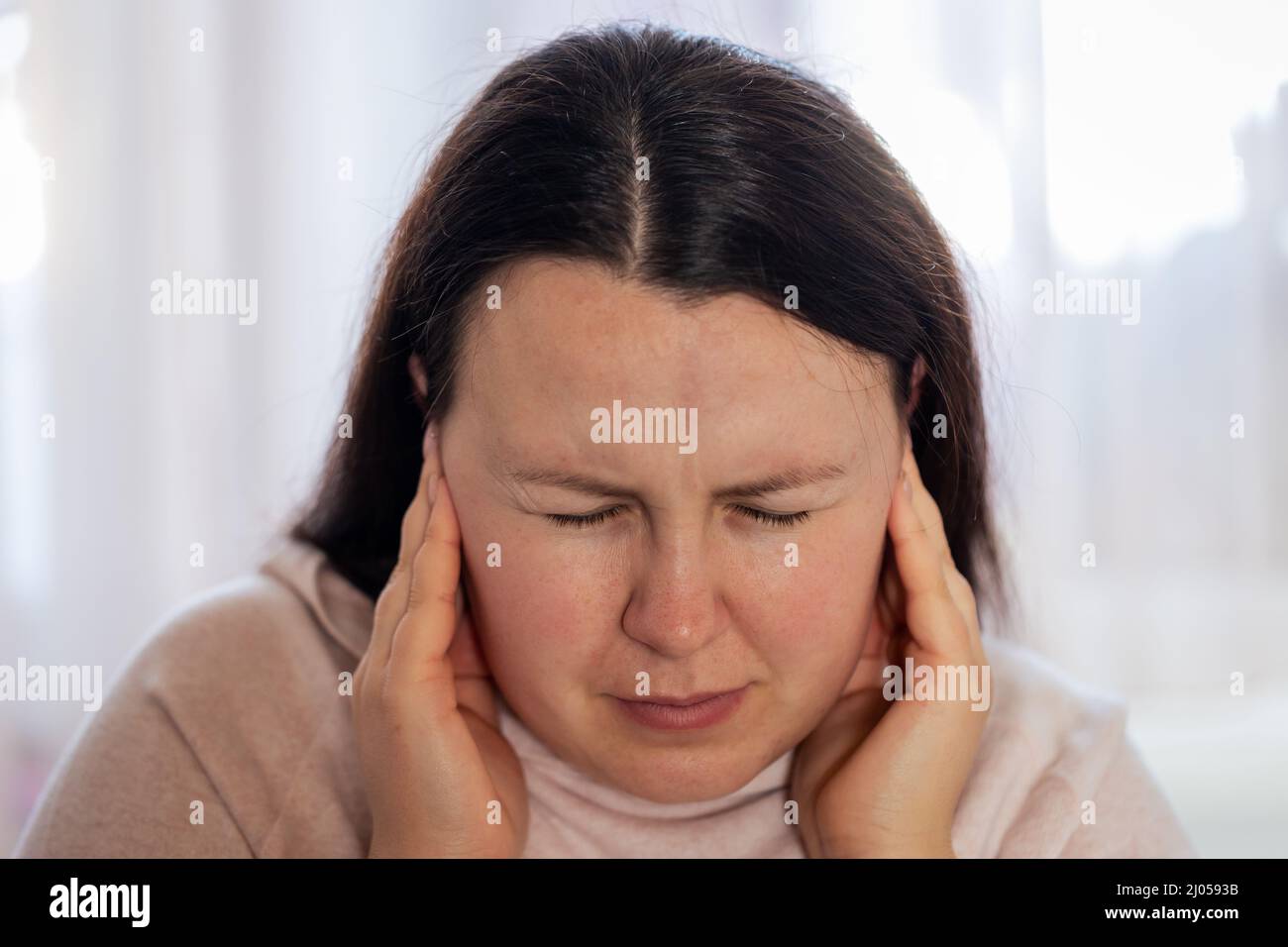 Junge Frau, die an Tinnitus-Krankheit, Schlaflosigkeit oder Stresskonzept leidet, kranke Frau, die Ohrenschmerzen hat, die ihren schmerzhaften Kopf berühren, Gesundheitskonzept Stockfoto