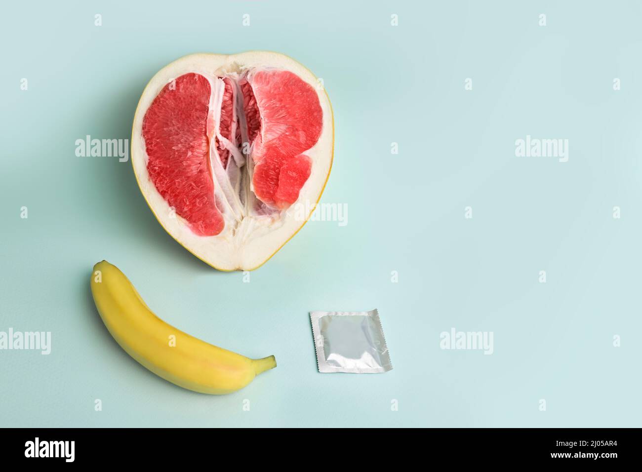 Sicherer Sex. Saftige Grapefruit und Banane in einem Kondom. Das Symbol der Vagina und des Penis aus der Frucht Stockfoto