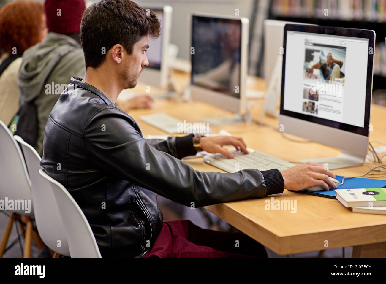 Sammeln von Fakten online. Aufnahme von Studenten, die an Computern in einer Universitätsbibliothek arbeiten. Stockfoto