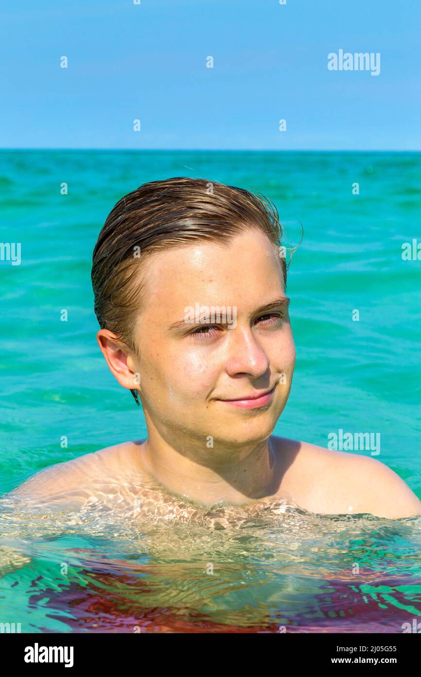 hübscher Teen hat Spaß Schwimmen im Ozean unter blauem Himmel Stockfoto