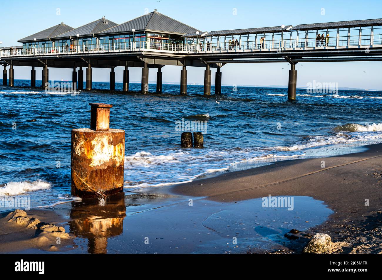 Ein rostiger Pol am ostseestrand vor dem Pier. Stockfoto