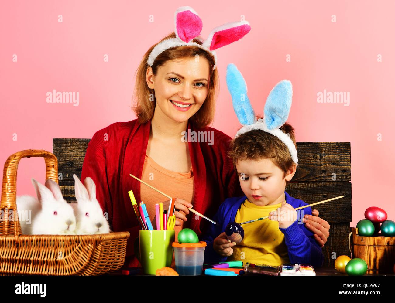 Mutter und Kind malen Ostereier. Glückliche Familie in Hasen Ohren. Ostertraditionen. Frühlingsferien. Stockfoto