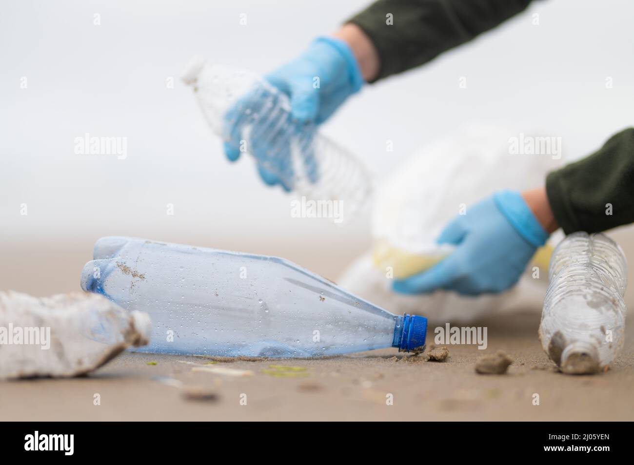 Makroaufnahme. Ein Freiwilliger reinigt gebrauchte Plastikflaschen an einem Sandstrand. Ökologische und soziale Probleme, Umweltschutz, Natur, Ökologie, wa Stockfoto