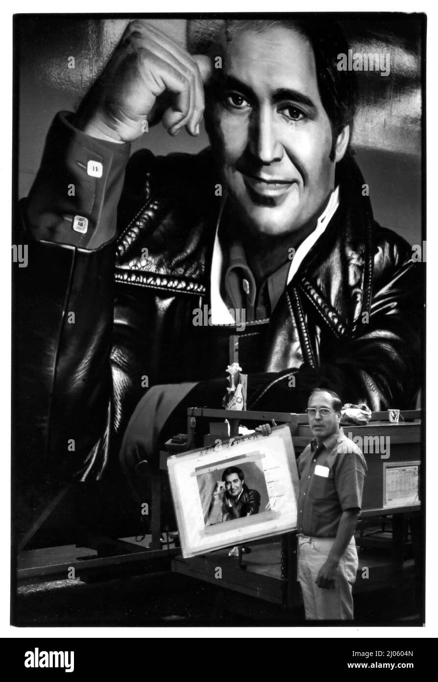 Werbetafel-Meister Mario Rueda, der 1977 vor seinem großen handgemalten Bild des Musikstars Neil Sedaka im Foster & Kleiser-Werbetafel-Studio in Los Angeles, CA, stand. Stockfoto