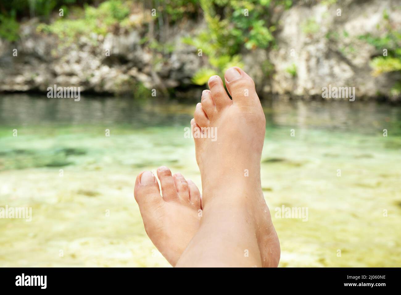 Weibliche Füße entspannen auf Cenote Stockfoto