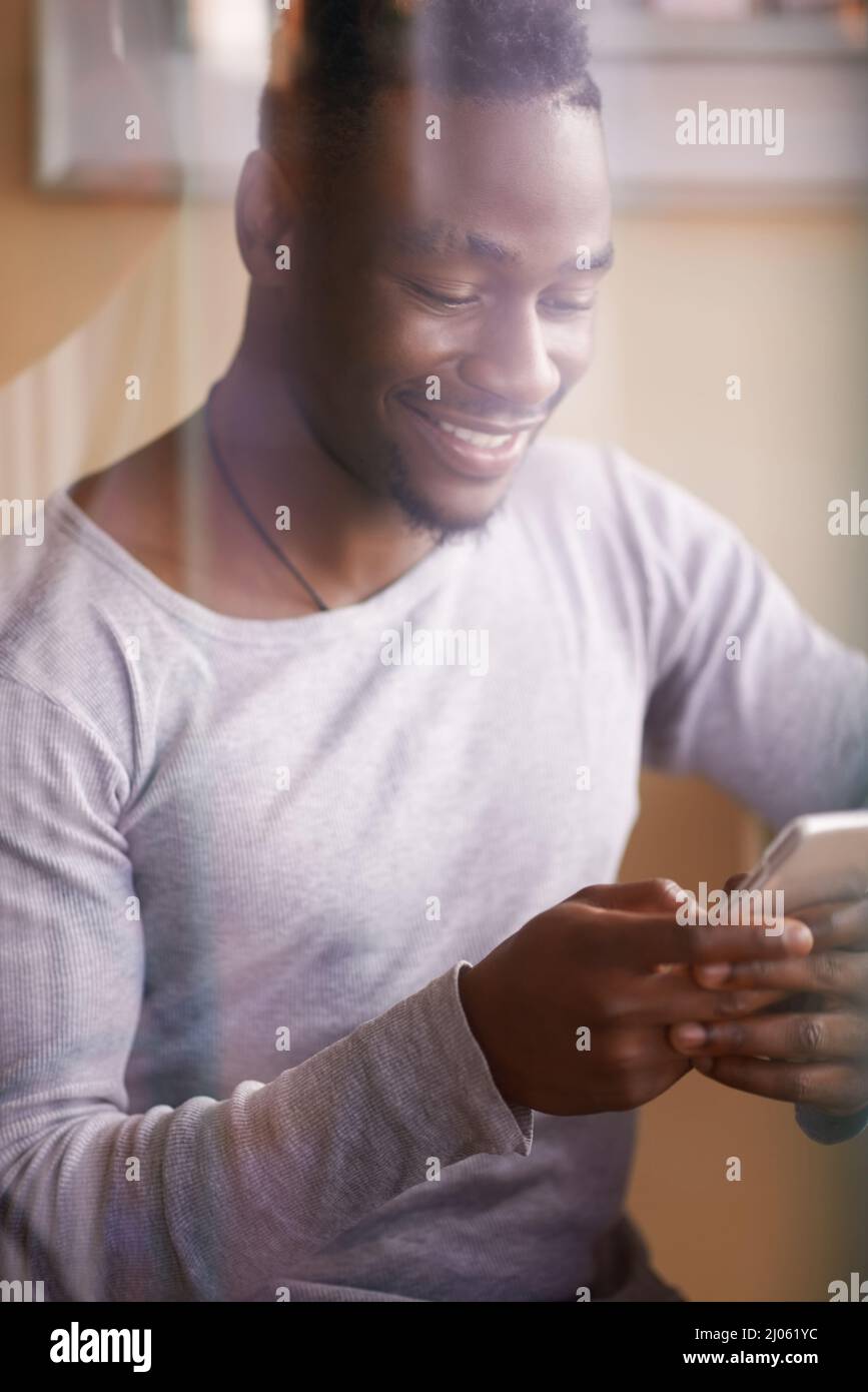 Ich warte auf Sie an unserem Lieblingsort. Ausgeschnittene Aufnahme eines hübschen jungen Mannes, der sein Telefon benutzt, während er in einem Café sitzt. Stockfoto