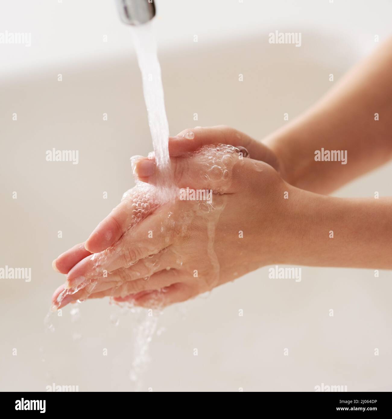 Beim Reiben abspülen. Abgeschnittene Aufnahme der Hände, die mit fließendem Wasser gewaschen wurden. Stockfoto