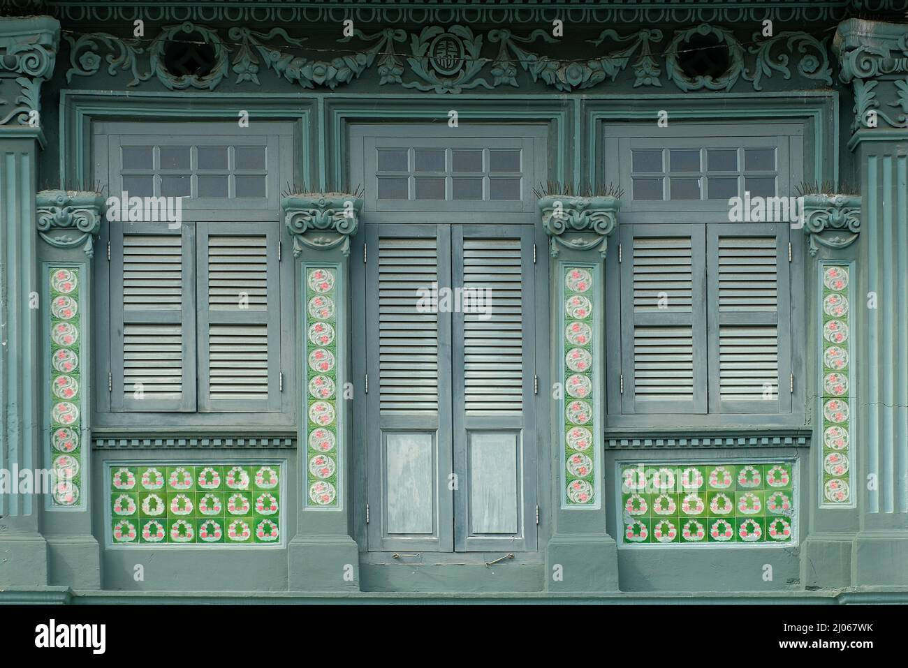 Grüne Straße Chinesisches Peranakan-Ladenhaus mit Holzlustern, Rokoko-Motiven, floralen Mosaikfliesen mit Taiji-Symbol und stilisiertem chinesischen Glückssymbol Stockfoto