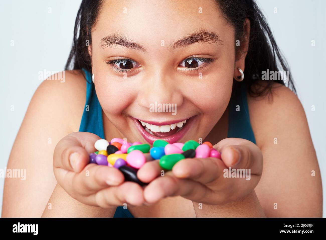 Mein Schatz. Studio-Aufnahme eines niedlichen jungen Mädchens mit einer Handvoll farbenfroher Gelee-Bohnen. Stockfoto