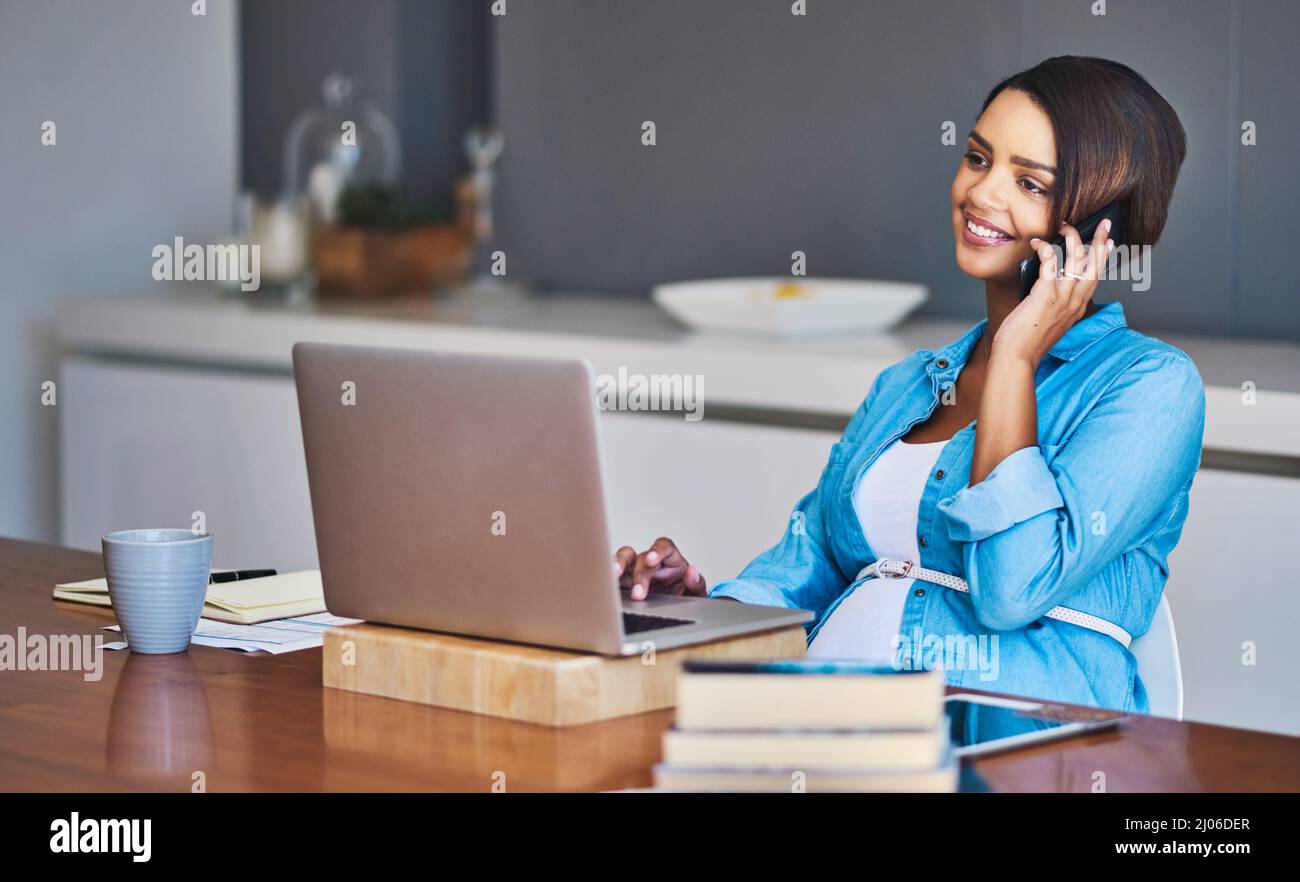 Ein Baby und ein brandneues Geschäft zu wachsen. Aufnahme einer schwanger jungen Frau, die einen Laptop und ein Mobiltelefon benutzt, während sie von zu Hause aus arbeitet. Stockfoto
