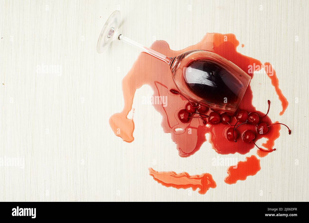 Betrunkene Kirschen. Studioaufnahme eines Weinglases mit Kirschen und Wein, der aus ihm ausläuft. Stockfoto