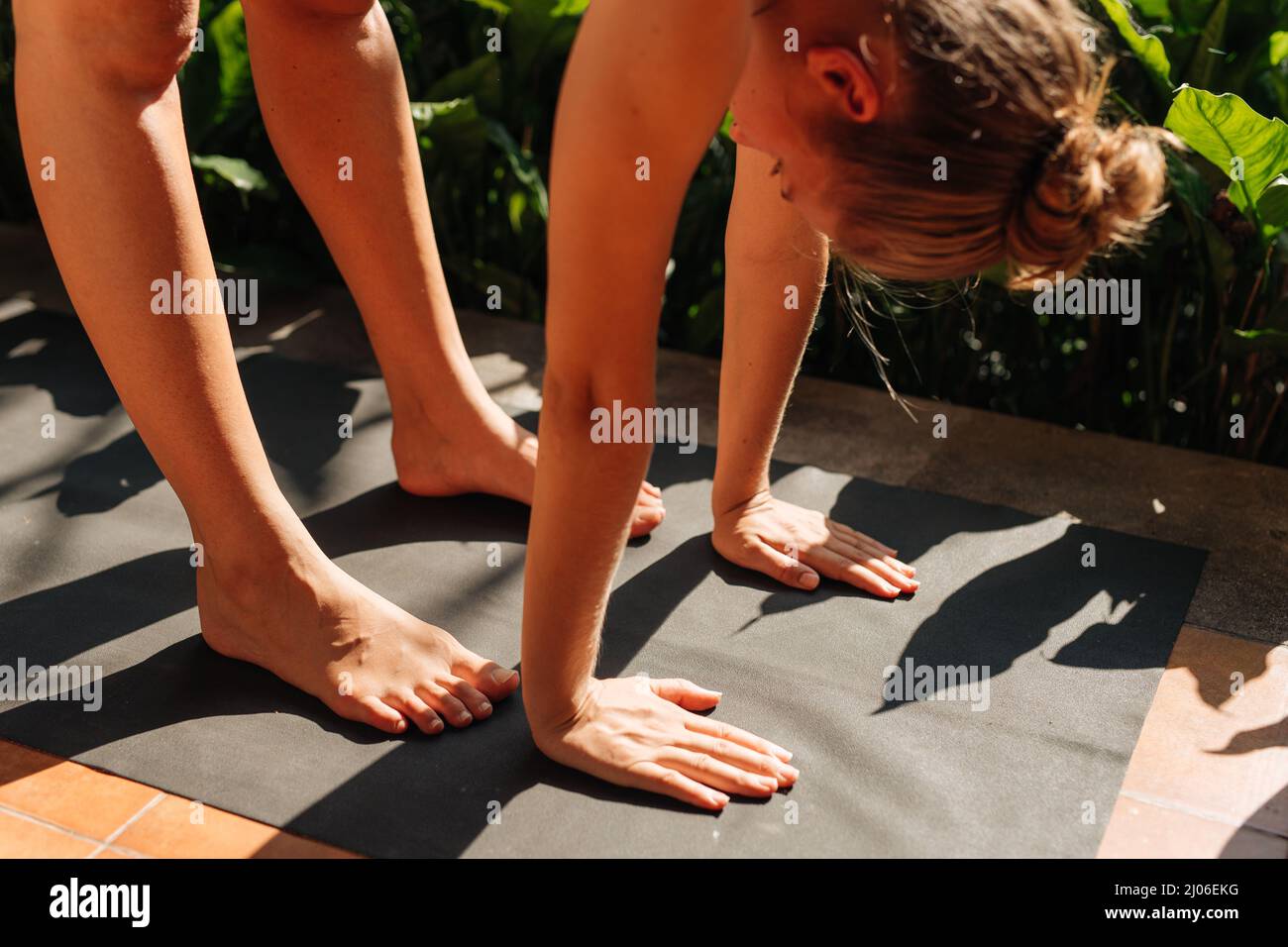 Schwangeren tun Yoga-Posen zu Hause mit Garten auf dem Hintergrund und umarmen ihren Bauch. Sonnenschein, sommerliche Stimmung Stockfoto