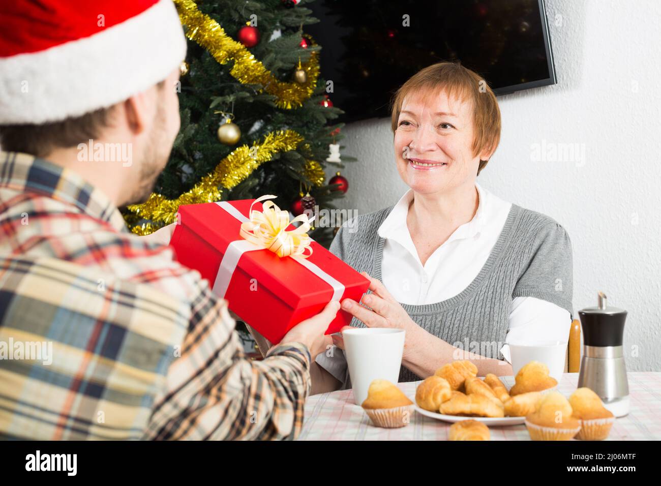 Erwachsener Sohn und Mutter, die Geschenke zu Weihnachten zu Hause Stockfoto