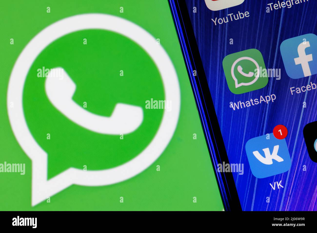 Das Icon der Whatsapp Messenger-Anwendung unter anderem auf dem Smartphone-Bildschirm. Auf dem Hintergrund ist das Whatsapp Logo zu sehen. Stockfoto