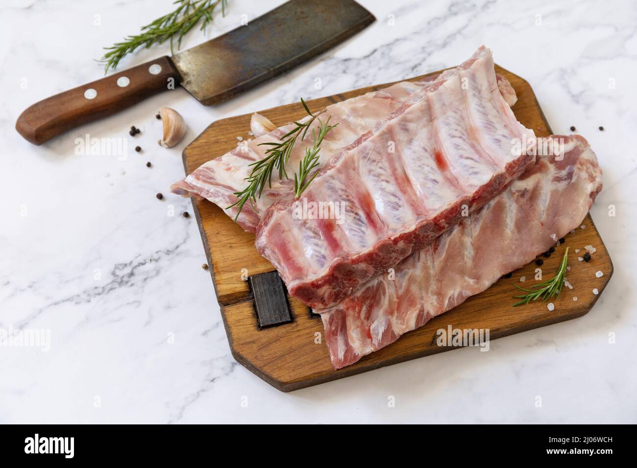 Rohes Kalbsbriketts Fleisch mit Rosmarin und Gewürzen auf kurzen Rippen zum Kochen auf Marmorplatte. Stockfoto
