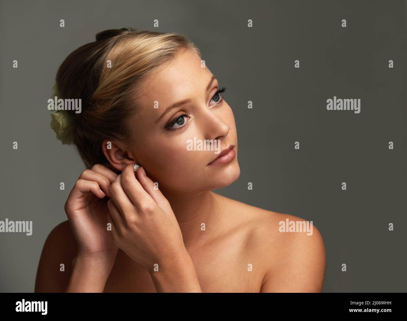 Einige kurzfristige Anpassungen vornehmen. Studioaufnahme einer schönen jungen Frau, die Ohrringe anlegt. Stockfoto
