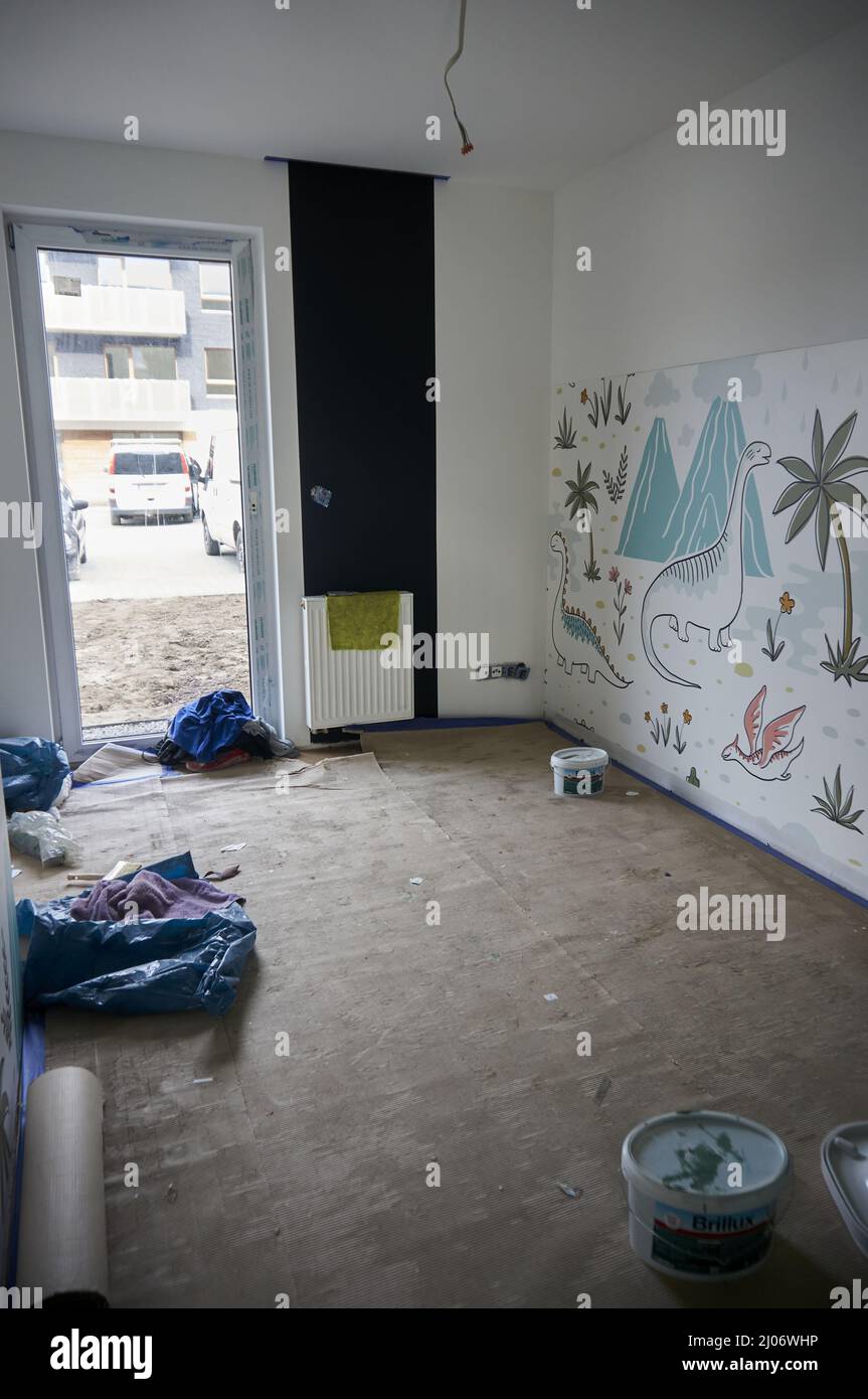 Kinder spielen in einem renovierten Zimmer mit Dinosaurierzeichnungen an der Wand in einem Apartment Stockfoto