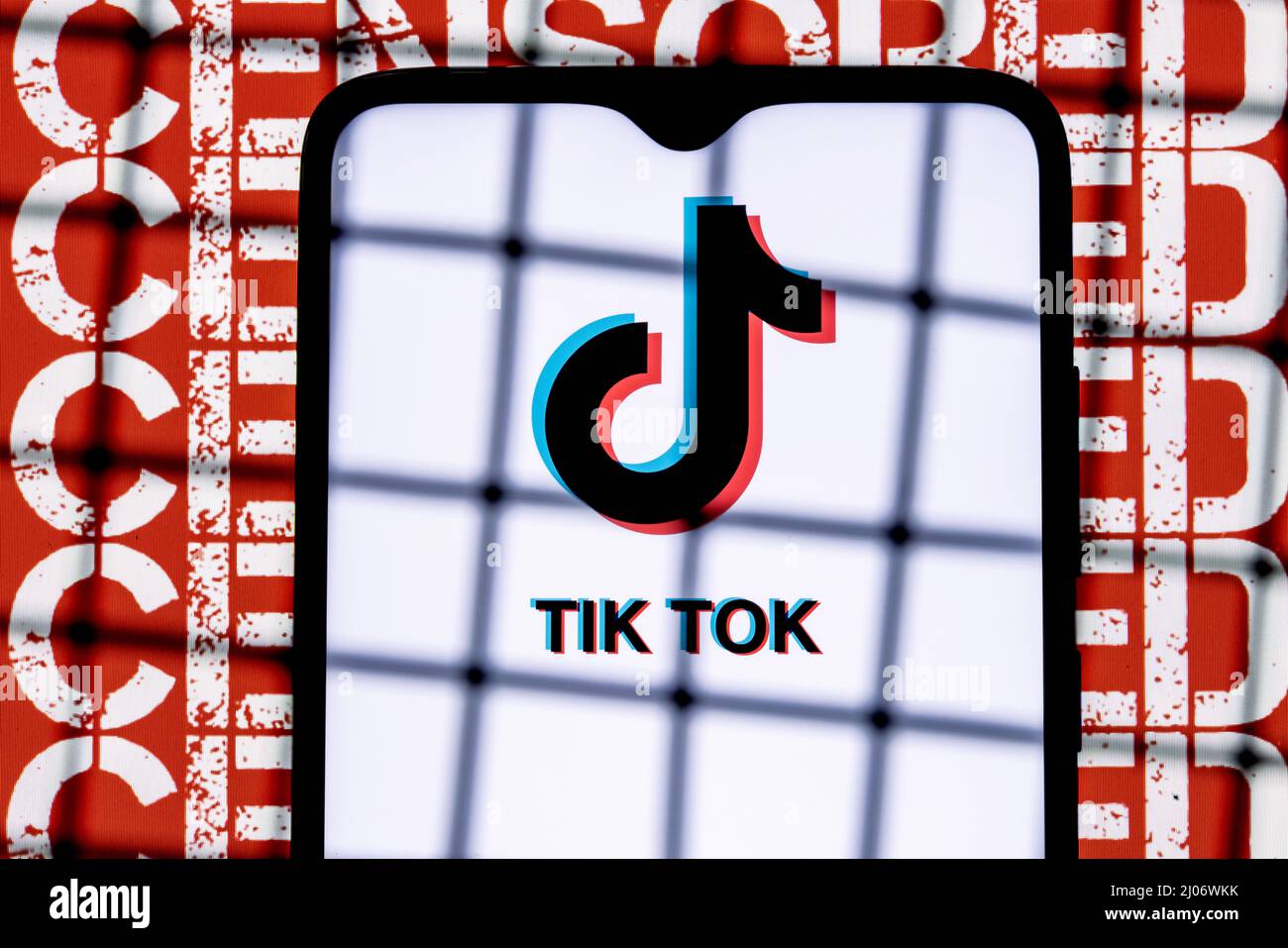 Logo des sozialen Netzwerks TikTok auf dem Smartphone-Bildschirm hinter den Balken im Hintergrund mit der Aufschrift zensiert. Stockfoto