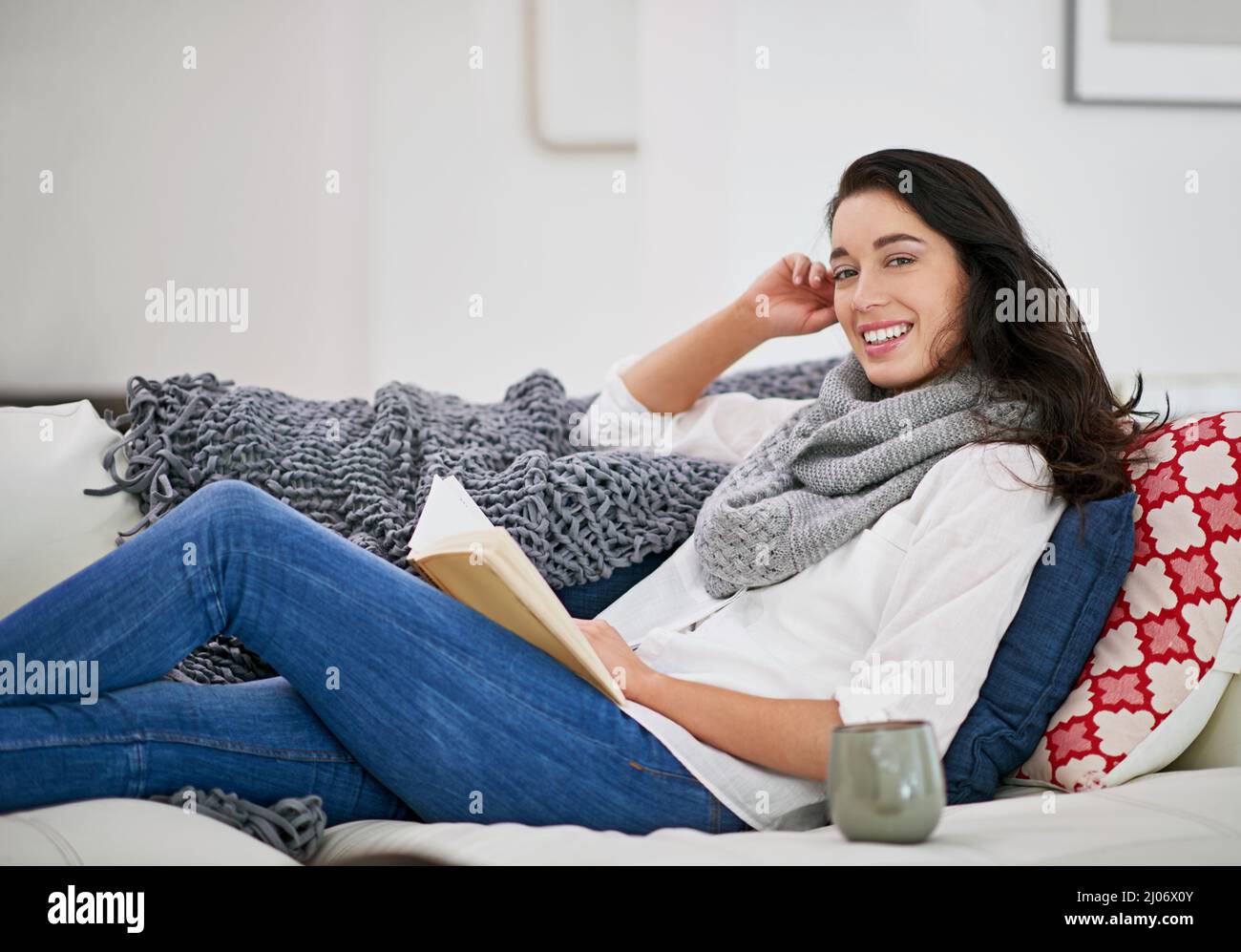 Es gibt keine Freunde, die so loyal sind wie ein Freund. Aufnahme einer jungen Frau, die ein Buch liest, während sie im Wohnzimmer sitzt. Stockfoto
