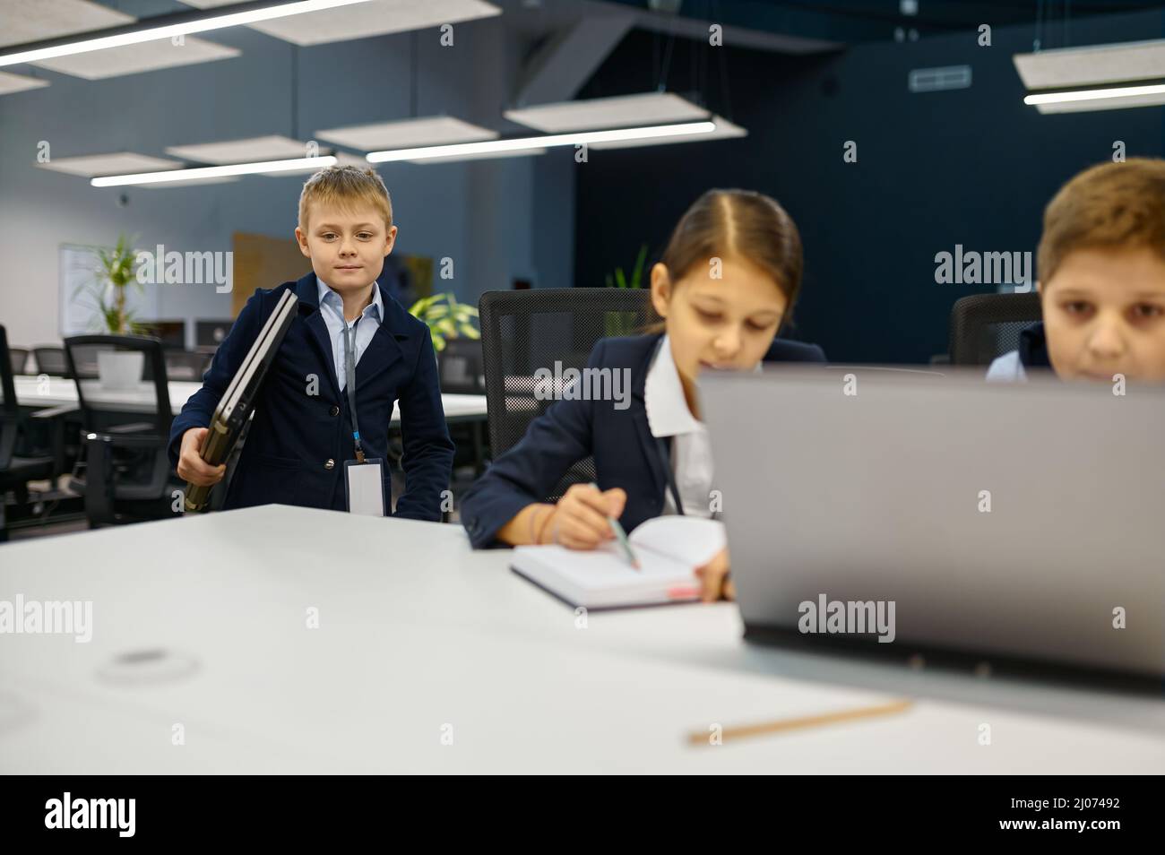 Kinder, die im modernen Büro an einem Laptop arbeiten Stockfoto