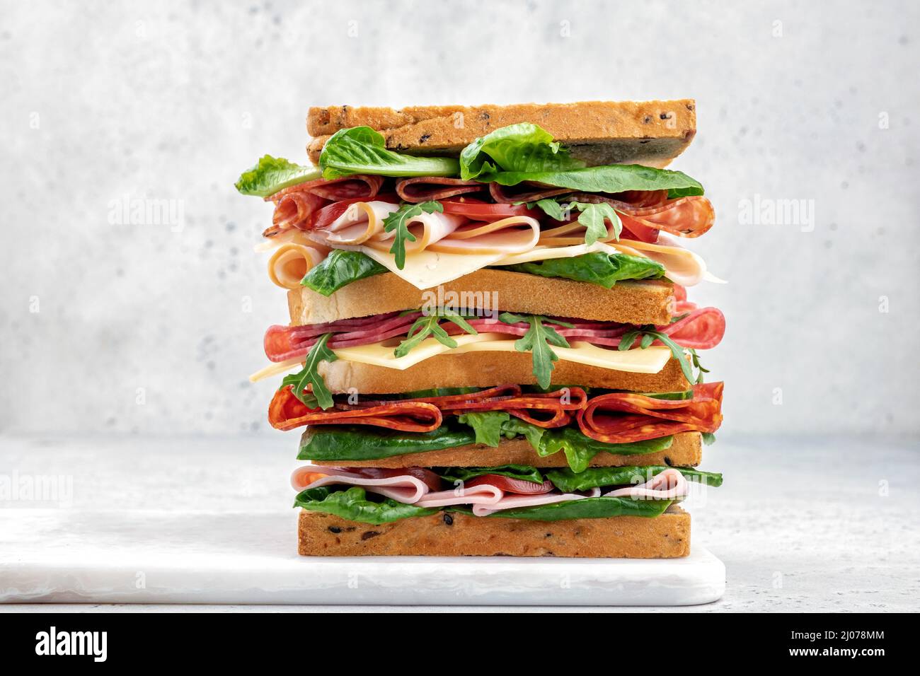 Großes leckeres Sandwich mit Schinken, Salami, Salat, Käse und Tomaten Stockfoto