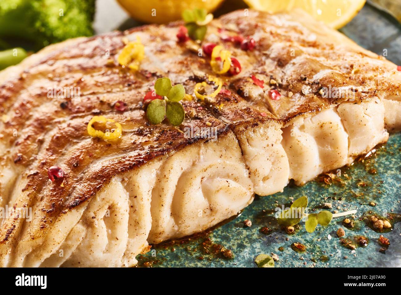 Nahaufnahme von appetitlich gegrilltem Fischfilet mit Kräutern, serviert auf dem Teller im Restaurant Stockfoto