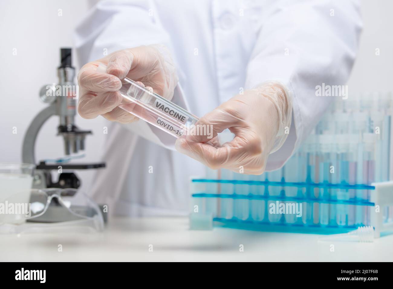 Mikrobiologe hält mit Schutzhandschuhen biologische Impfstoffröhrchen auf Laborhintergrund. Hinter der wissenschaftlichen Entdeckung. Gesundheitswesen und medi Stockfoto